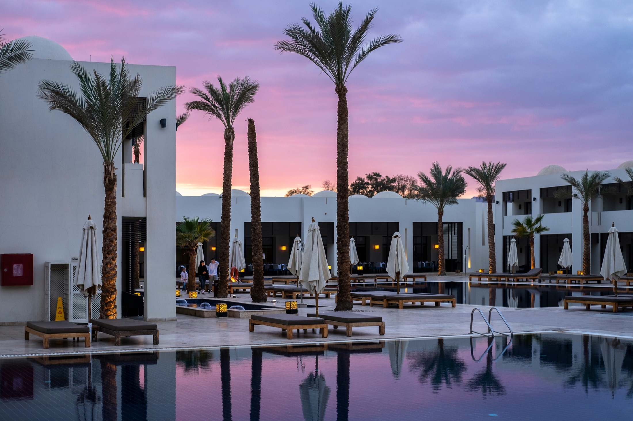 A resort pool beneath palms at sunset